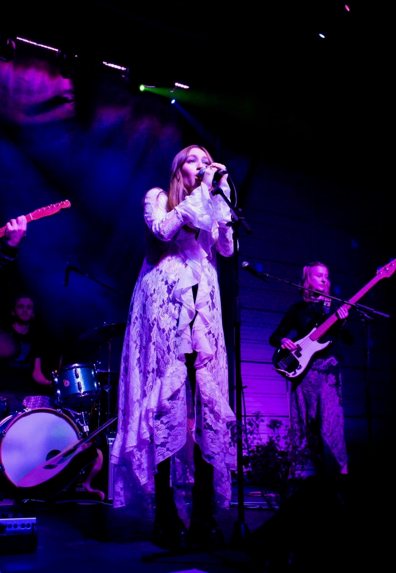 Emma Grace Burton singing onstage with her band under violet lights
