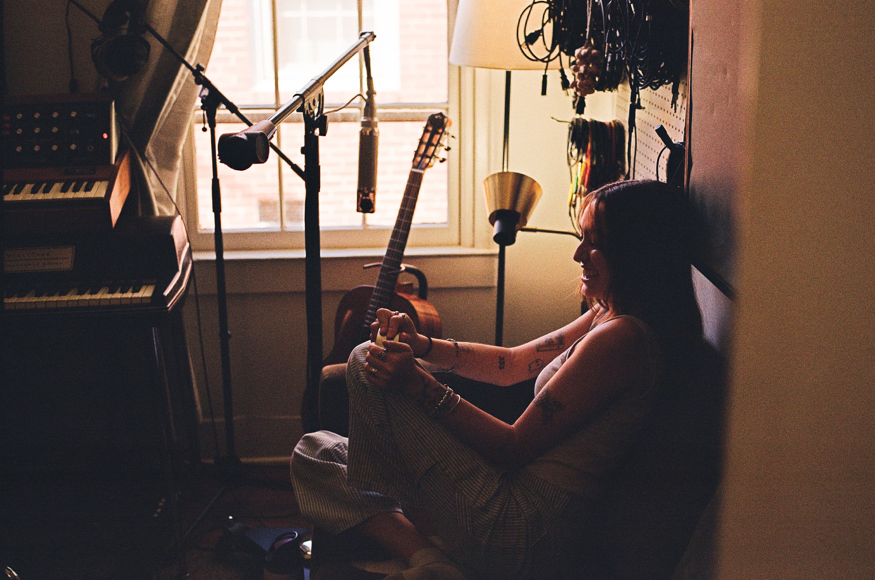 Emma Grace Burton sitting in a sunlit music studio